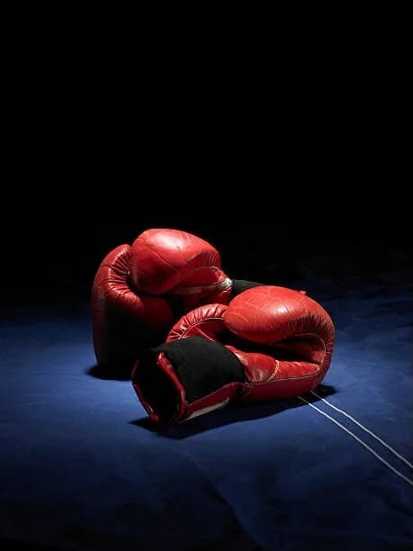 Pair of red leather boxing gloves on a dark blue canvas
