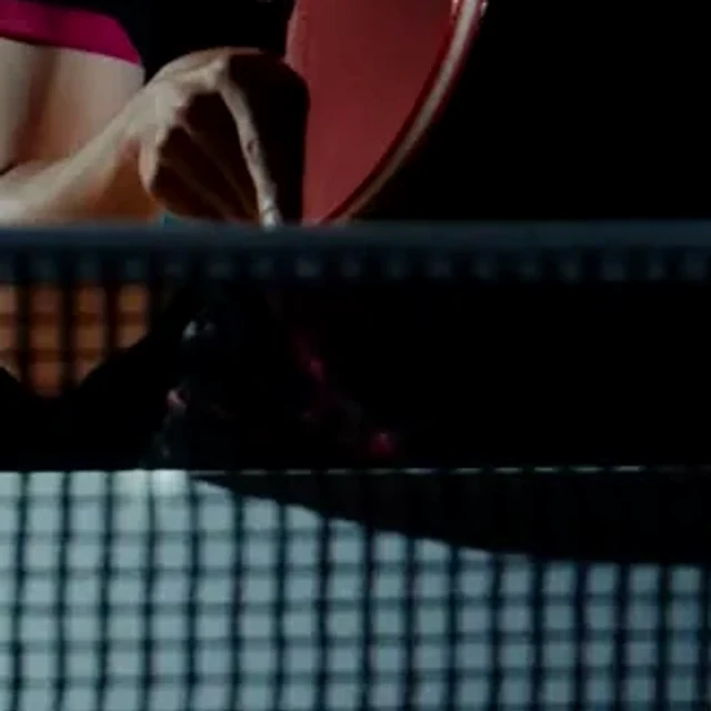 Hand gripping a table tennis racket above the net